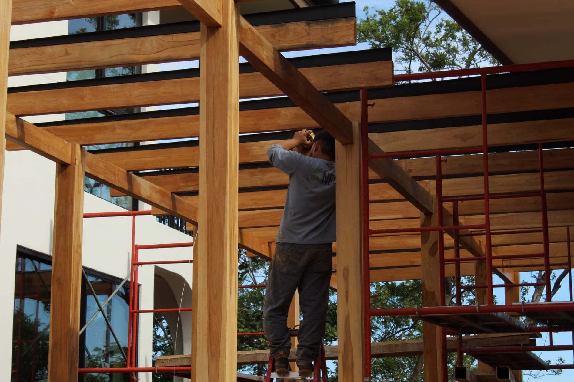 Nest Construction crew member installing a wood pergola roof structure in Guanacaste, Costa Rica