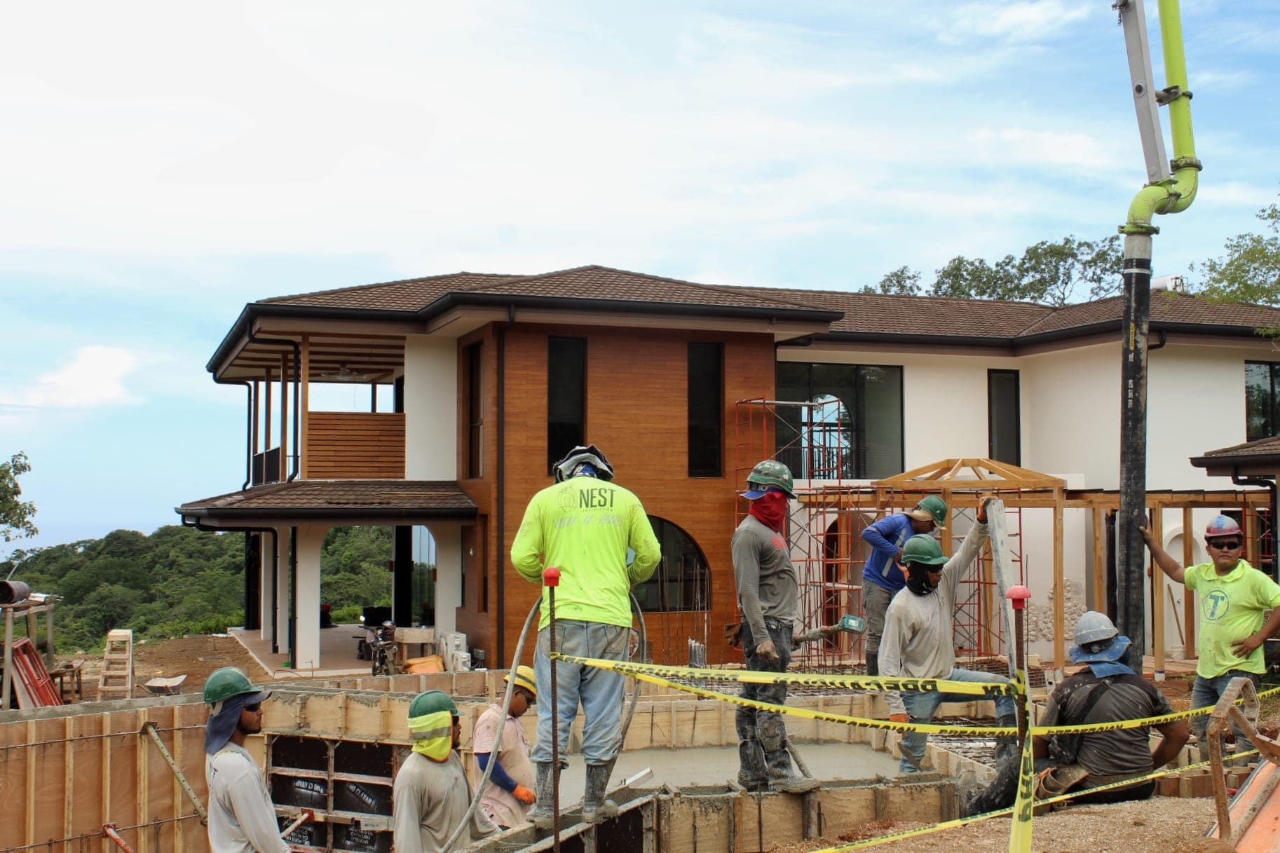 Nest Construction crew pouring concrete in front of a hillside home under construction in Nosara, Costa Rica